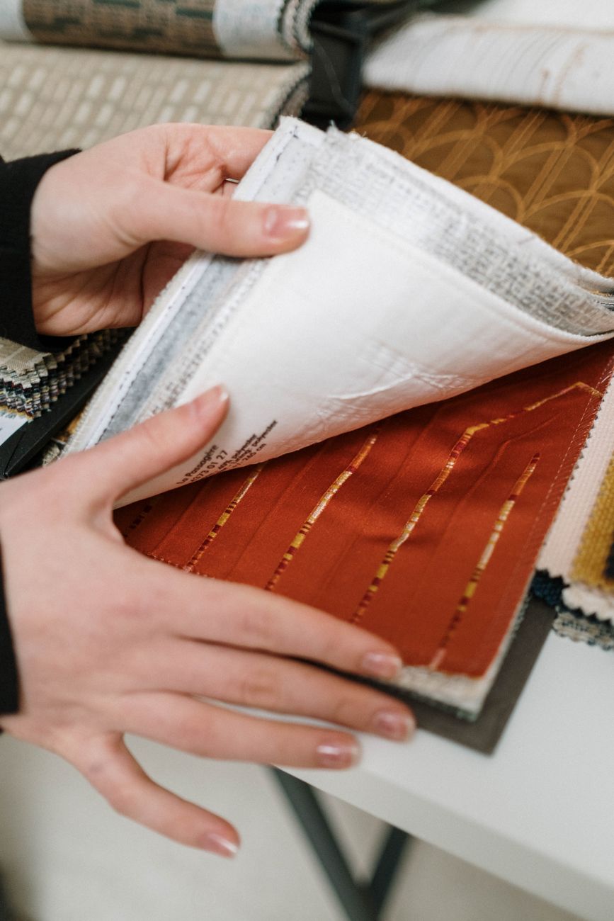 Hands turning the pages of a fabric swatch book on a studio table